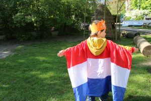 Ein Kita-Kind mit Niederlande-Fahne und Krone am Königstag