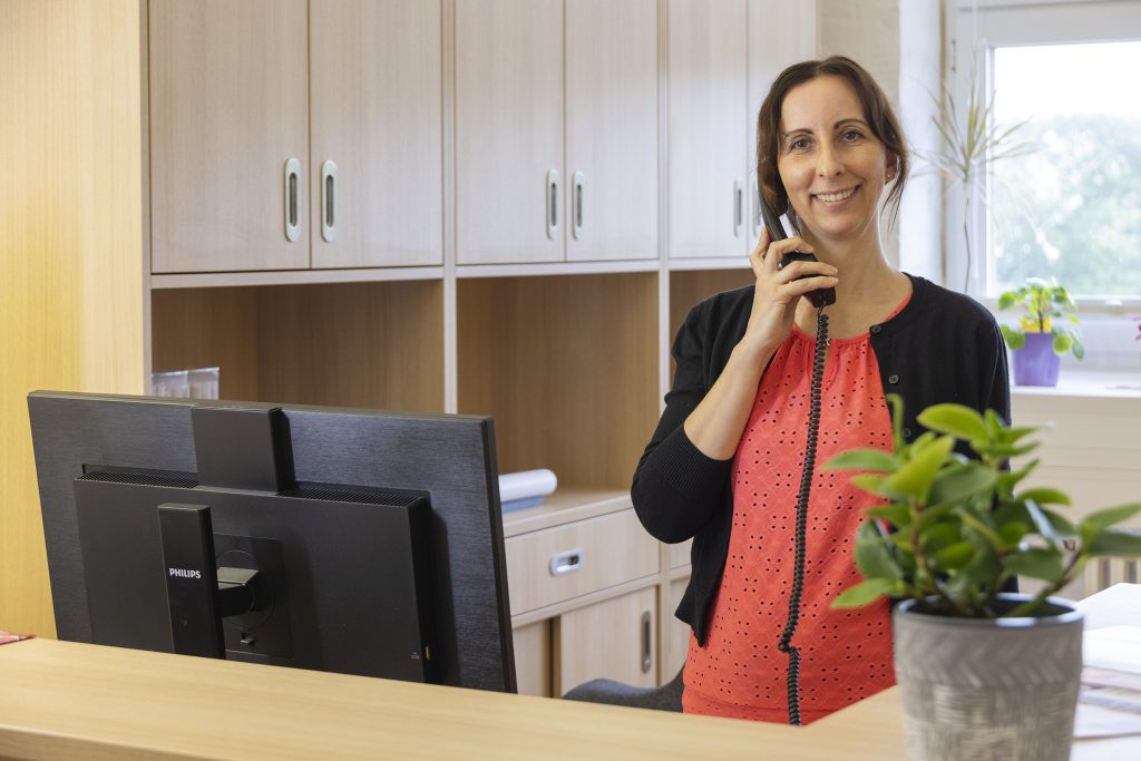Eine Frau steht in einem Büro. Die Frau telefoniert mit einem Telefon.